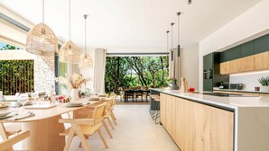 Een moderne keuken met een centraal eiland, houten stoelen en hanglampen.