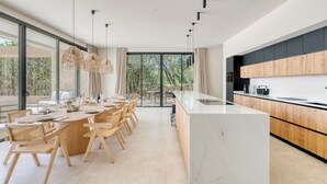 Een moderne keuken met een groot eiland, houten kasten en een eethoek met een lange tafel en stoelen.