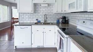 A modern kitchen with white cabinetry, a stainless steel sink, and a built-in oven. - The PennHaus - Peaceful Home Near Lake CDA & Shops (Coeur d'Alene)