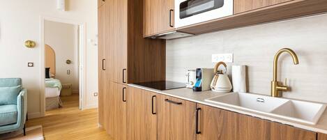 A modern kitchen with wooden cabinets, a built-in oven, and a stainless steel sink.