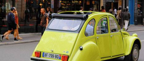 A vintage yellow car parked on a city street.