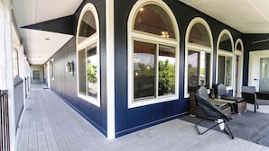 A covered porch with a dark blue exterior, large arched windows, and outdoor seating area with a grill. - Direct access to the lake, short drive to all the Branson fun! (Kimberling City)