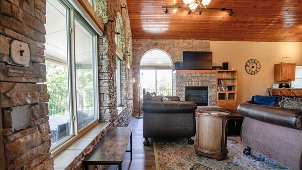 A cozy living room with stone walls, a fireplace, and comfortable seating. - Direct access to the lake, short drive to all the Branson fun! (Kimberling City)