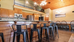 A kitchen with wooden cabinets, a stainless steel refrigerator, and a bar area with stools. - Direct access to the lake, short drive to all the Branson fun! (Kimberling City)