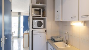 Une cuisine compacte équipée d’un four à micro-ondes, d’un petit réfrigérateur, d’un évier et d’un placard.