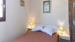 Une chambre à coucher avec un lit simple, deux tables de chevet, deux lampes et deux tableaux encadrés accrochés au mur.