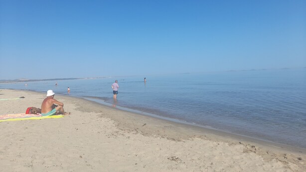 Een strand met mensen die ontspannen en zwemmen.