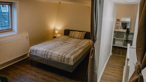 A bedroom with a bed, a bedside lamp, a window, a radiator, and a wooden floor. - Modern Apartment in Koblenz (Koblenz)