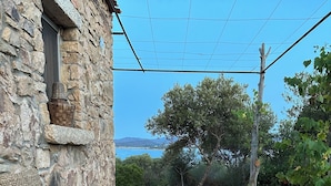 Un edificio in pietra con una finestra, un cesto in vimini e un tavolo con una bottiglia, un limone e una ciotola di verdure.