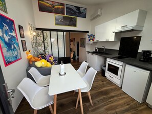 A compact kitchen with white cabinets, a black countertop, and a small oven. There is a dining area with a white table and chairs. - Modern House With Four Bedrooms in Loire (Le Mans)