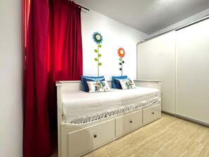 A bedroom with a bed, a red curtain, and two wall decorations. - Premium Apartment in Roquetas de Mar (Roquetas de Mar)