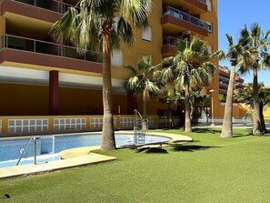 A multi-story building with balconies, a swimming pool, and palm trees. - Premium Apartment in Roquetas de Mar (Roquetas de Mar)