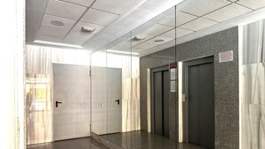 A corridor with a mirrored wall, a glass door, and a door with a sign. - Premium Apartment in Roquetas de Mar (Roquetas de Mar)