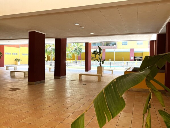 A spacious indoor area with tiled flooring, benches, and potted plants. - Premium Apartment in Roquetas de Mar (Roquetas de Mar)