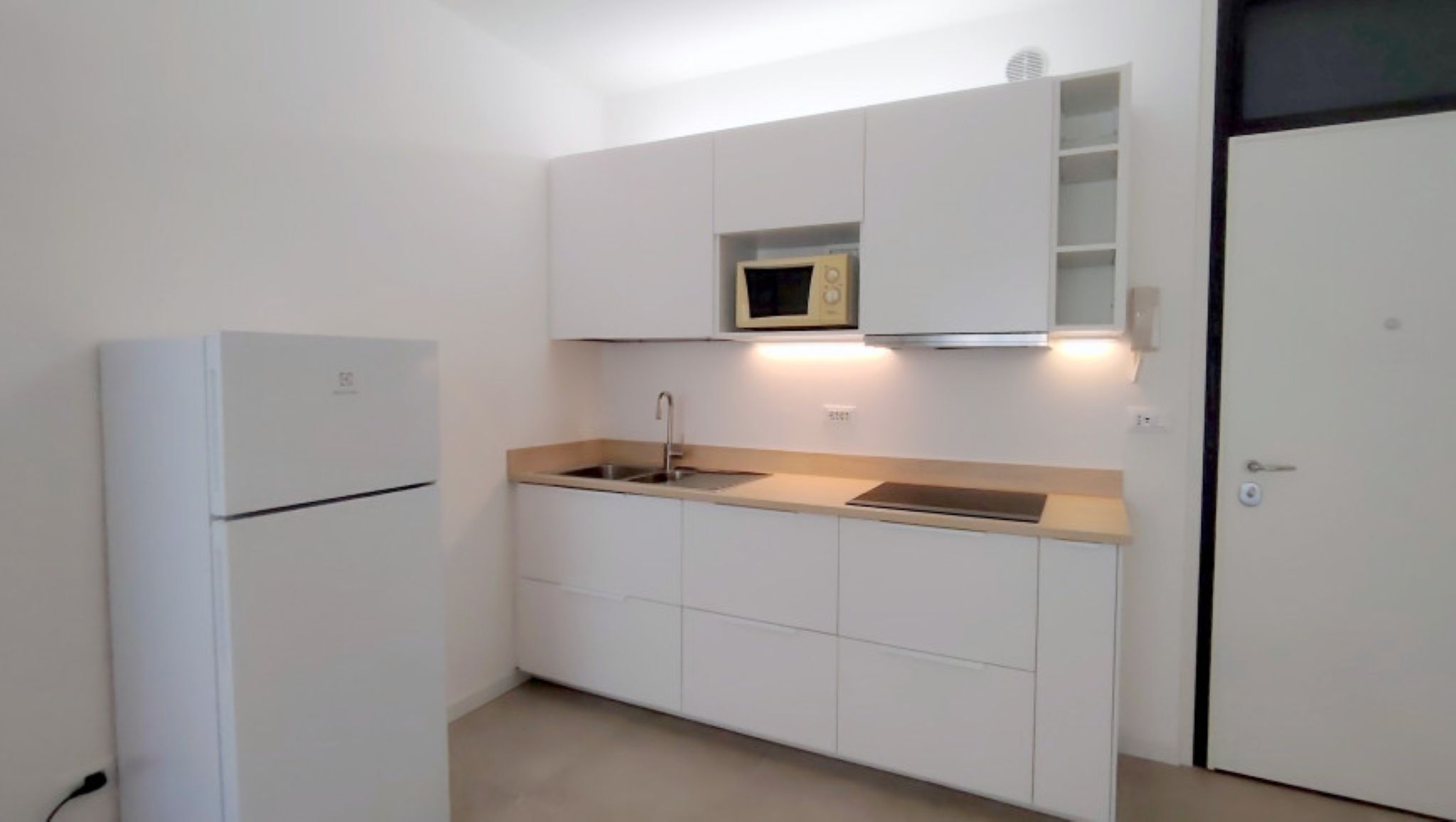 A compact kitchen with white cabinets, a built-in microwave, and a sink.
