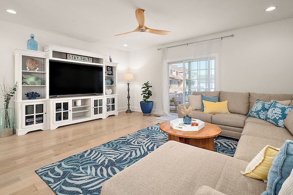 A living room with a TV, sofa, coffee table, and a ceiling fan.