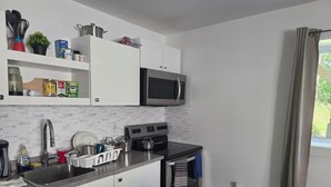 A modern kitchen with white cabinets, stainless steel appliances, and a window with curtains. - A Gorgeous 1bedroom Walkout Basement in a Serene Environment (Halifax)
