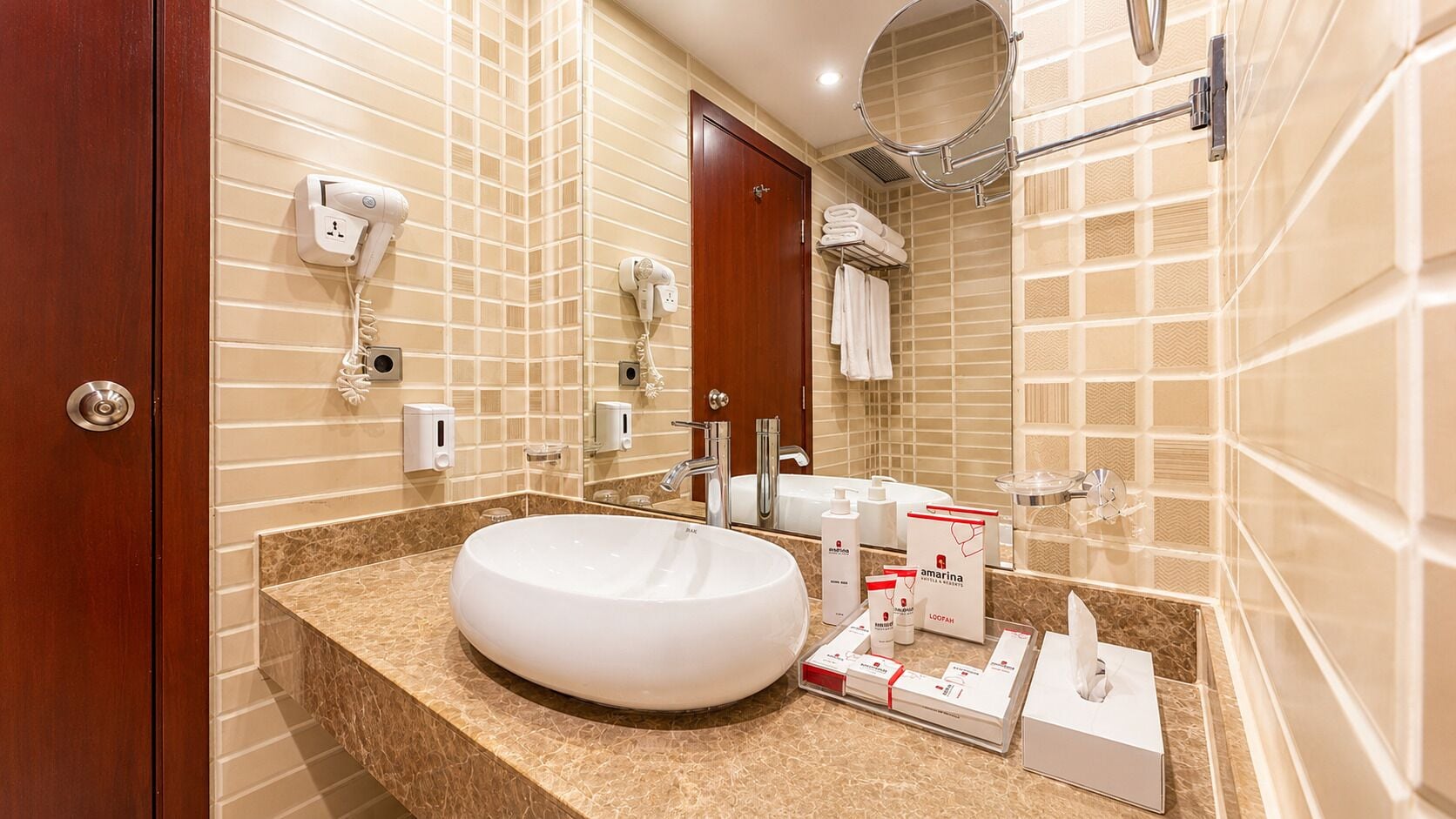A hotel bathroom with a large sink, towel rack, and a mirror.