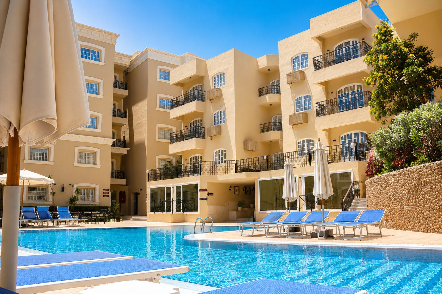 Um hotel com piscina, várias varandas e espreguiçadeiras.