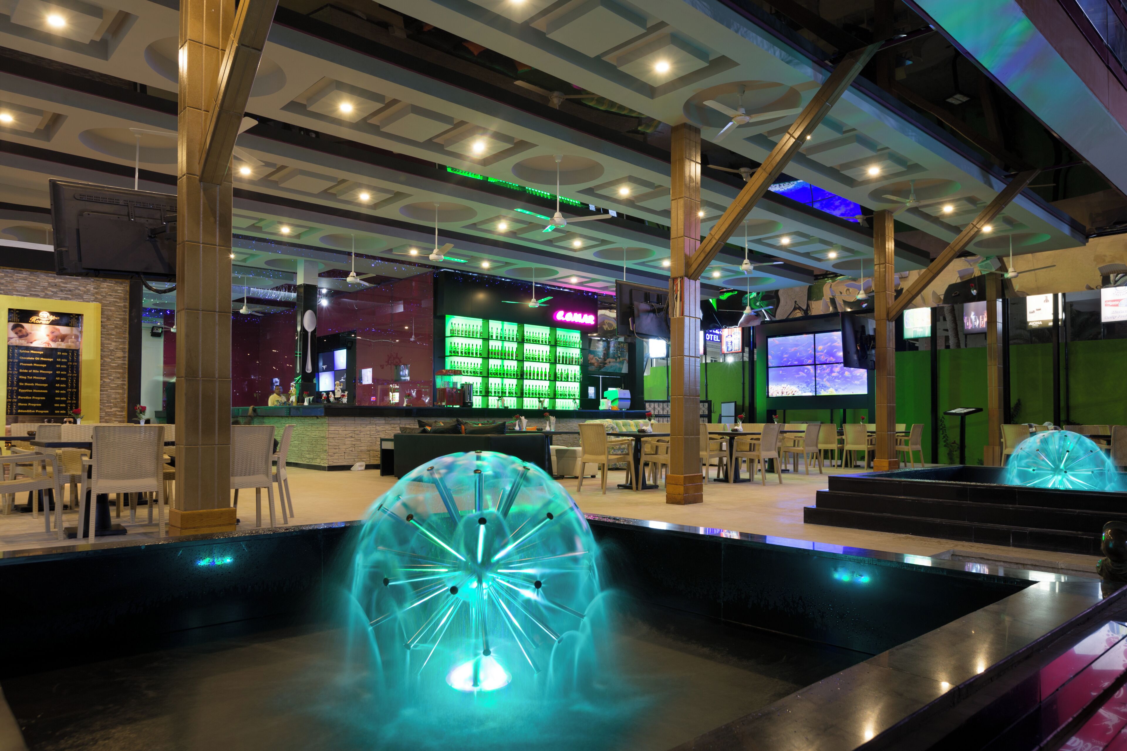 A modern indoor space with a bar area, seating, and a unique illuminated water feature.
