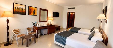 A hotel room with two beds, a desk, a chair, and a sofa.