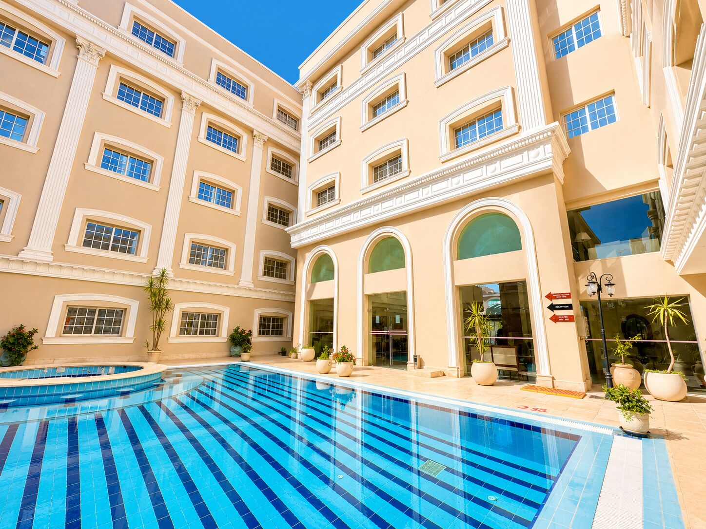 A hotel with a swimming pool, multiple floors, and a classical architectural style.
