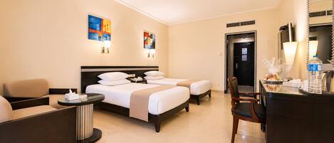 Een hotelkamer met een bed, twee nachtkastjes, een bureau, een stoel en een receptiehoek.