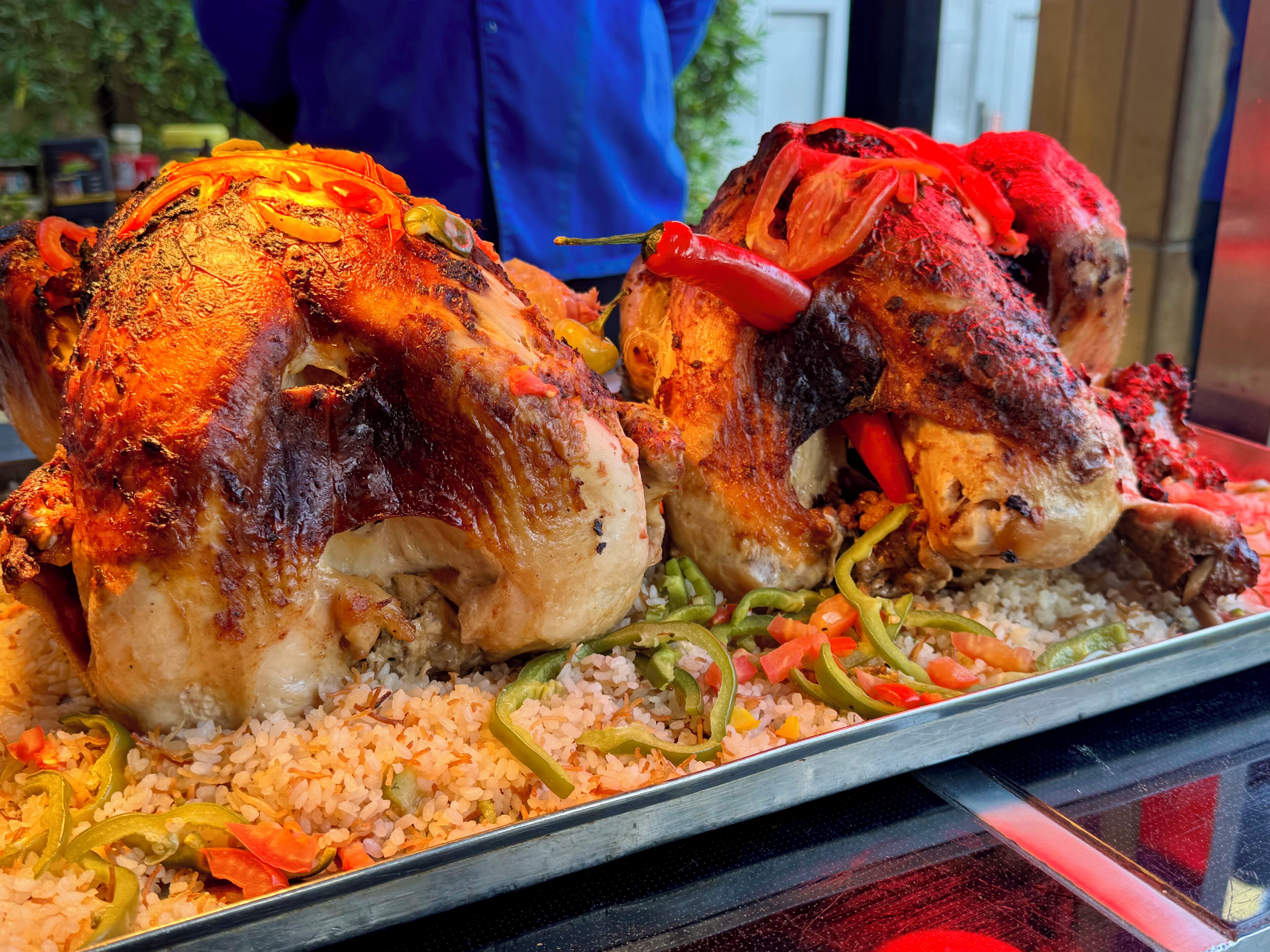 A roasted chicken with rice and bell peppers on a tray.