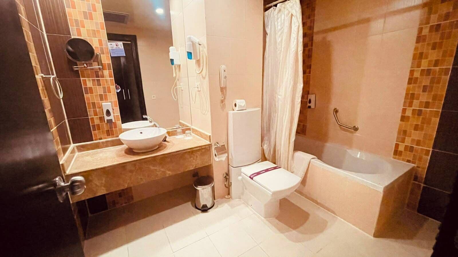 A bathroom with a sink, toilet, and bathtub, featuring a tiled wall and a mirror.