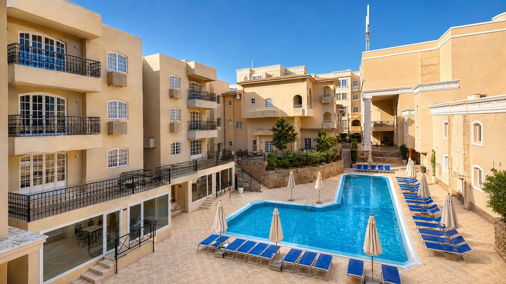 Un hotel con piscina, varios balcones y zonas de estar al aire libre.