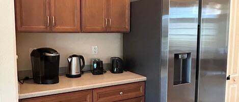 Eine Küche mit Holzausstattung, einem Edelstahlkühlschrank und einer Arbeitsplatte mit Kaffeemaschine, Toaster und Wasserkocher.