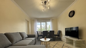 Ein Wohnzimmer mit Sofa, Fernseher und Essbereich.