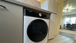 Eine moderne Küche mit einer weißen SABA Waschmaschine, einem Einbauofen und einem Essbereich mit Tisch und Stühlen.