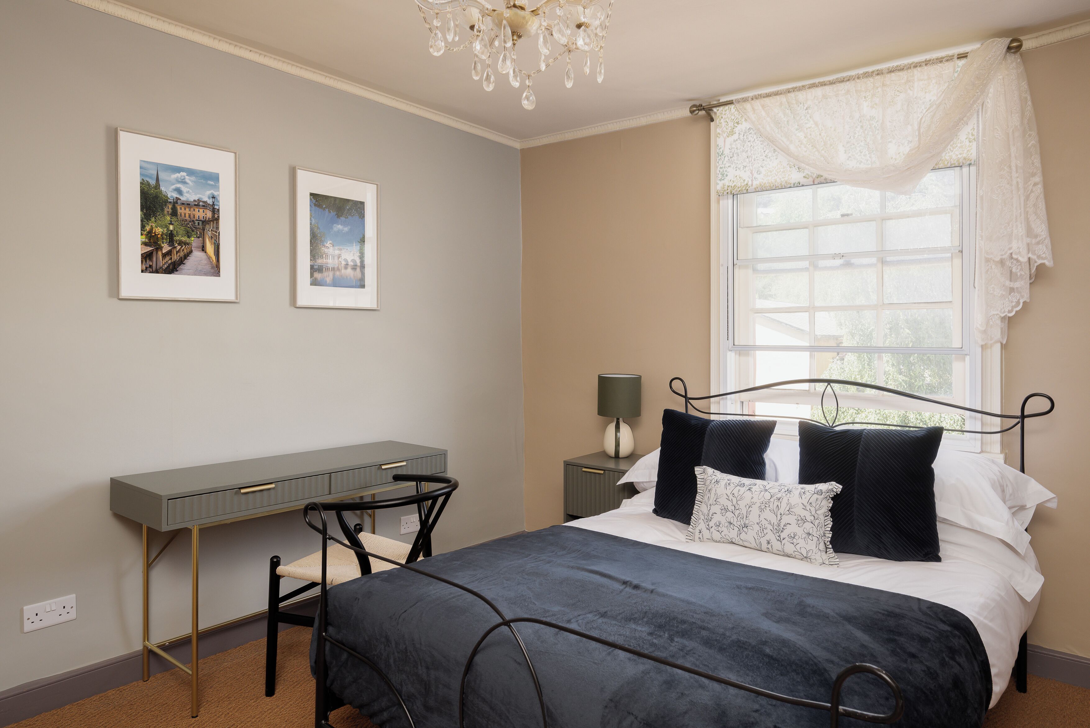 A bedroom with a bed, a desk, and two framed pictures on the wall.