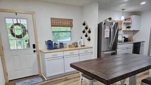 Eine moderne Küche mit weißen Schränken, einem Holztisch und einem eingebauten Kühlschrank.