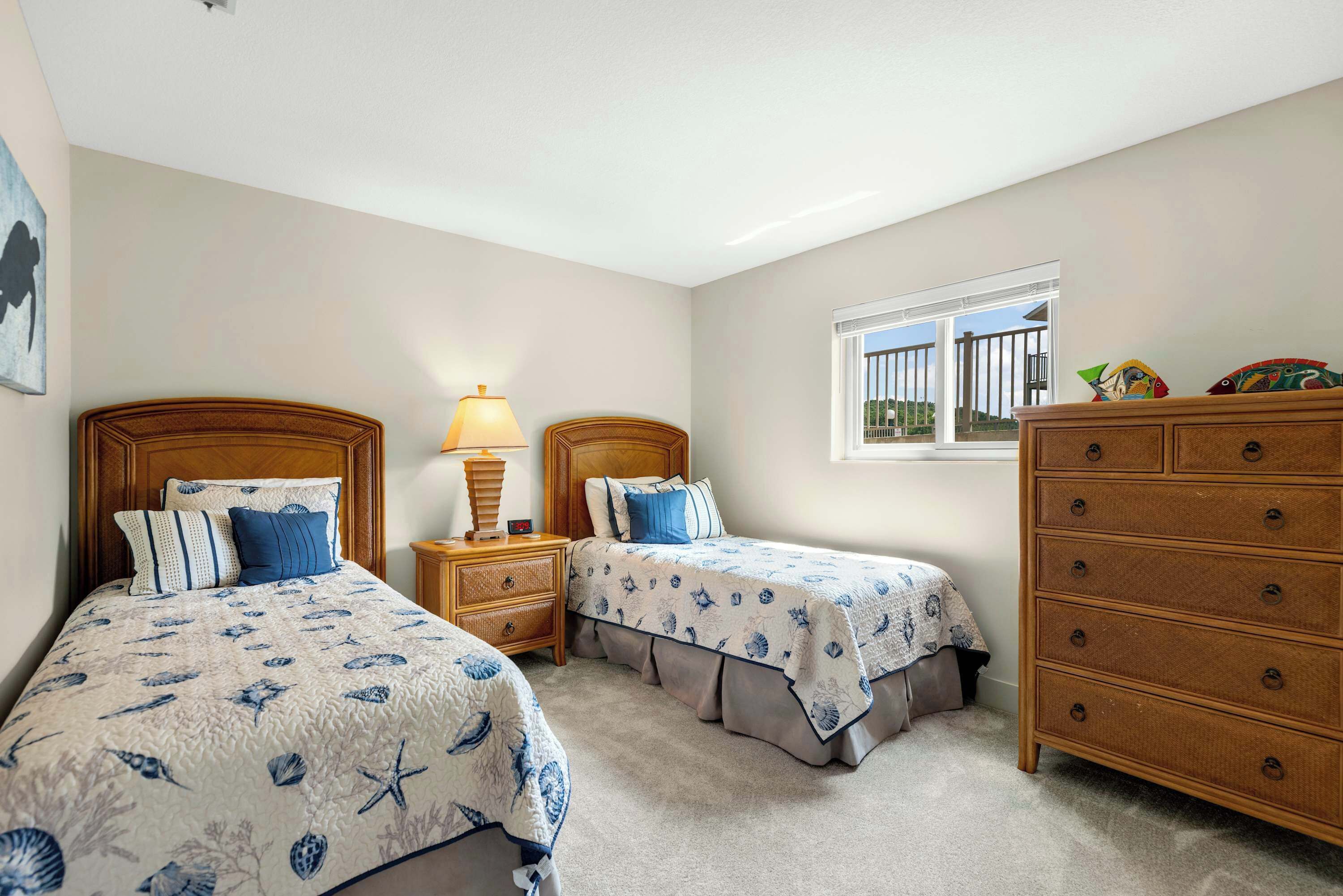 A bedroom with two beds, a dresser, and a window with a view.