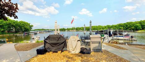 A riverside dock with covered items, a flag, and a boat.