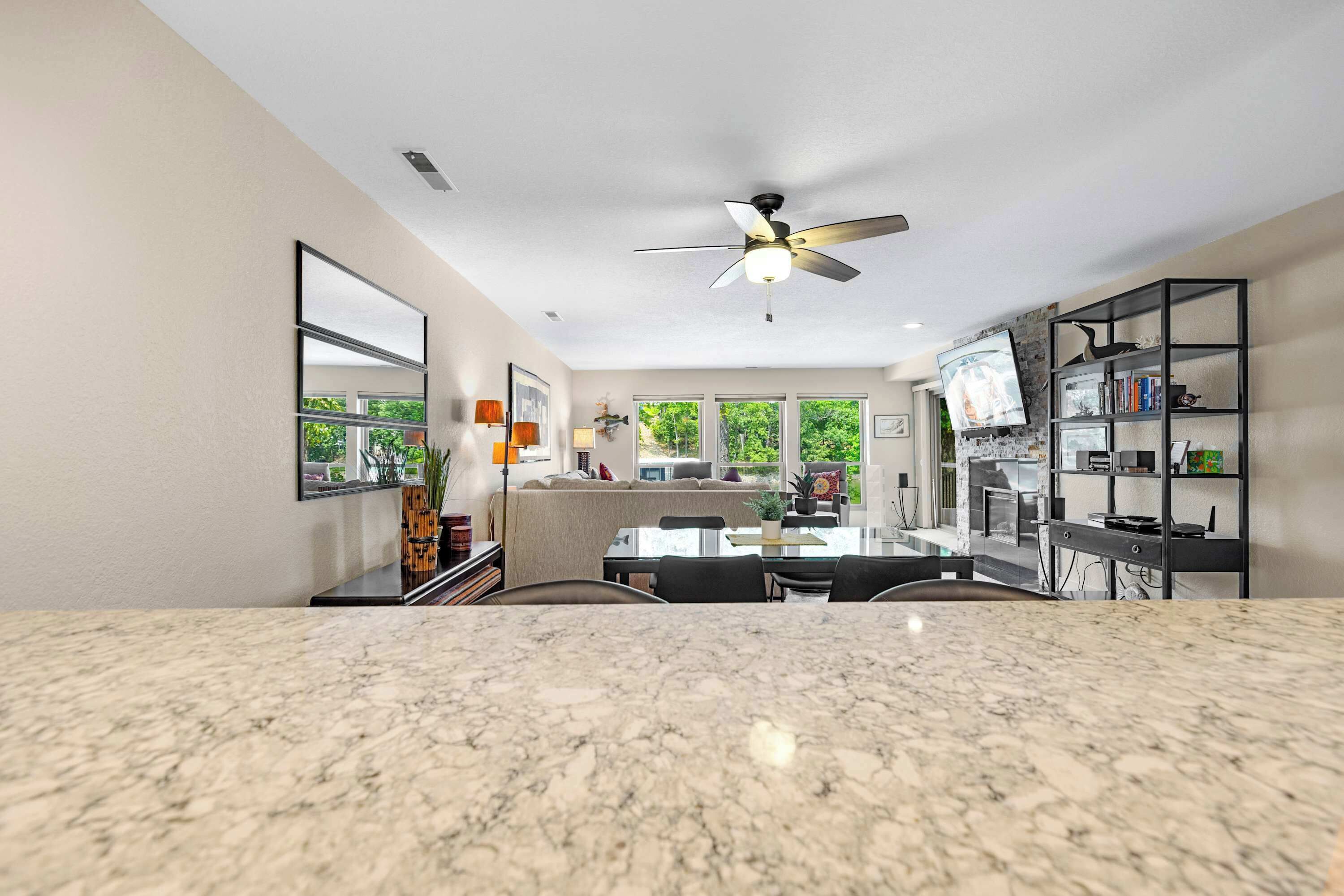 A modern kitchen with a granite countertop, a ceiling fan, and a dining area with a table and chairs.