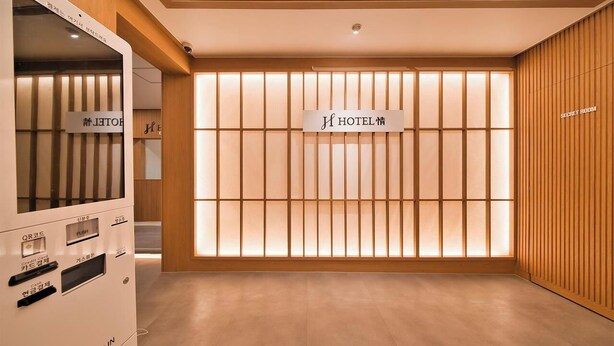 A hotel reception area with a check-in machine, a sign for the hotel, and a wooden wall with vertical slats.
