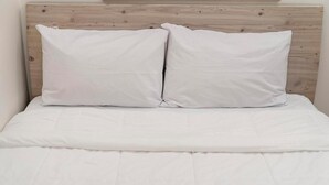 A bed with a wooden headboard and two white pillows.