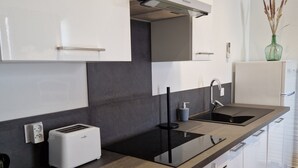 A modern kitchen with white cabinets, a black countertop, a built-in oven, and a stainless steel sink. - Chic & Central - Your Retreat in Le Mans (Le Mans)