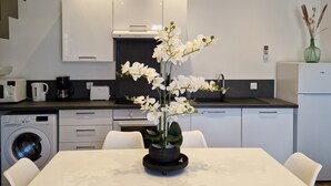 A modern kitchen with white cabinets, a built-in oven, and a dining area with a white table and chairs. - Chic & Central - Your Retreat in Le Mans (Le Mans)