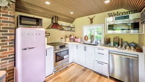 Una cucina moderna con mobili bianchi, elettrodomestici in acciaio inossidabile e un soffitto in legno.