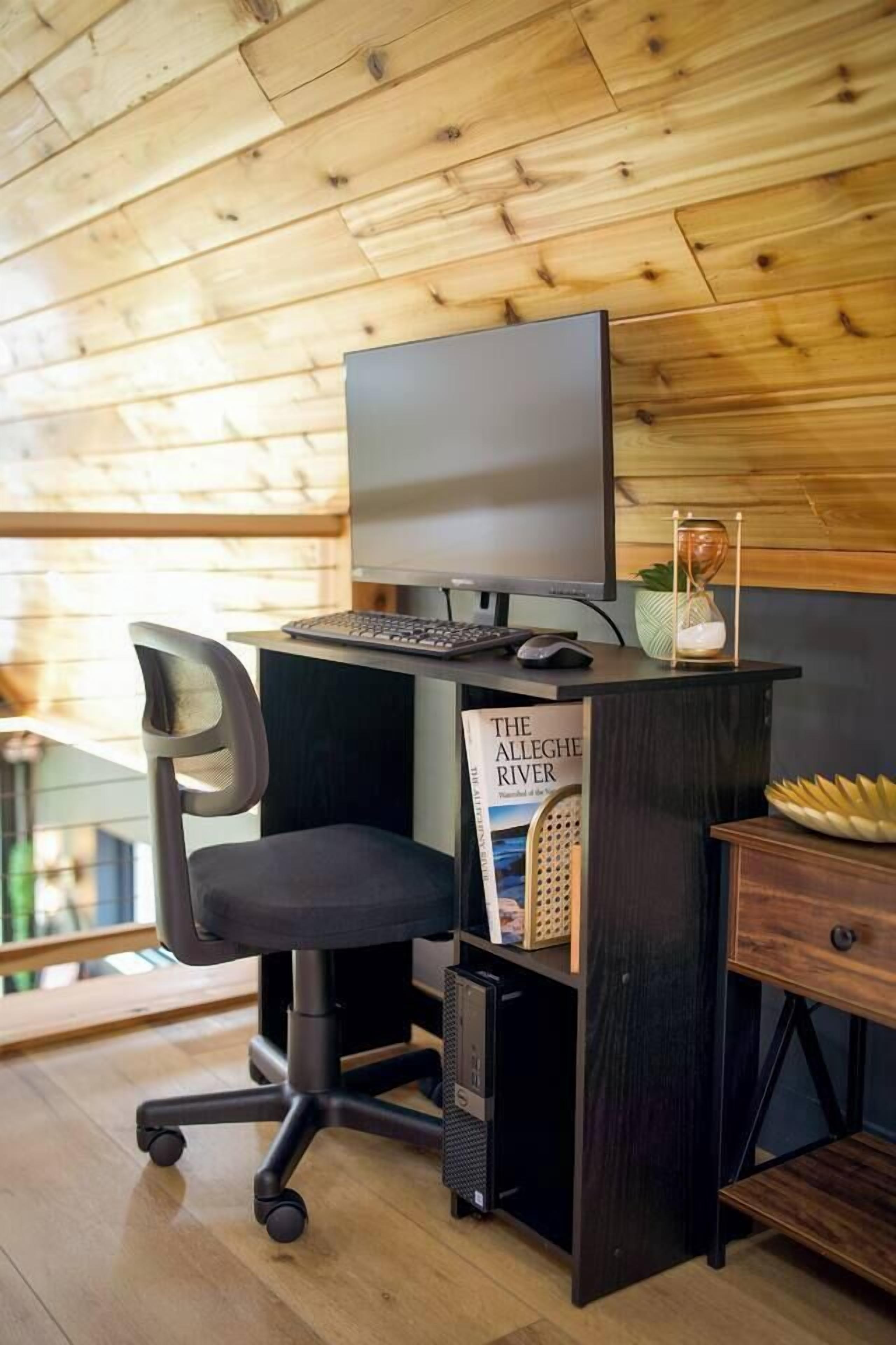 A modern office desk with a computer, chair, and bookshelf.