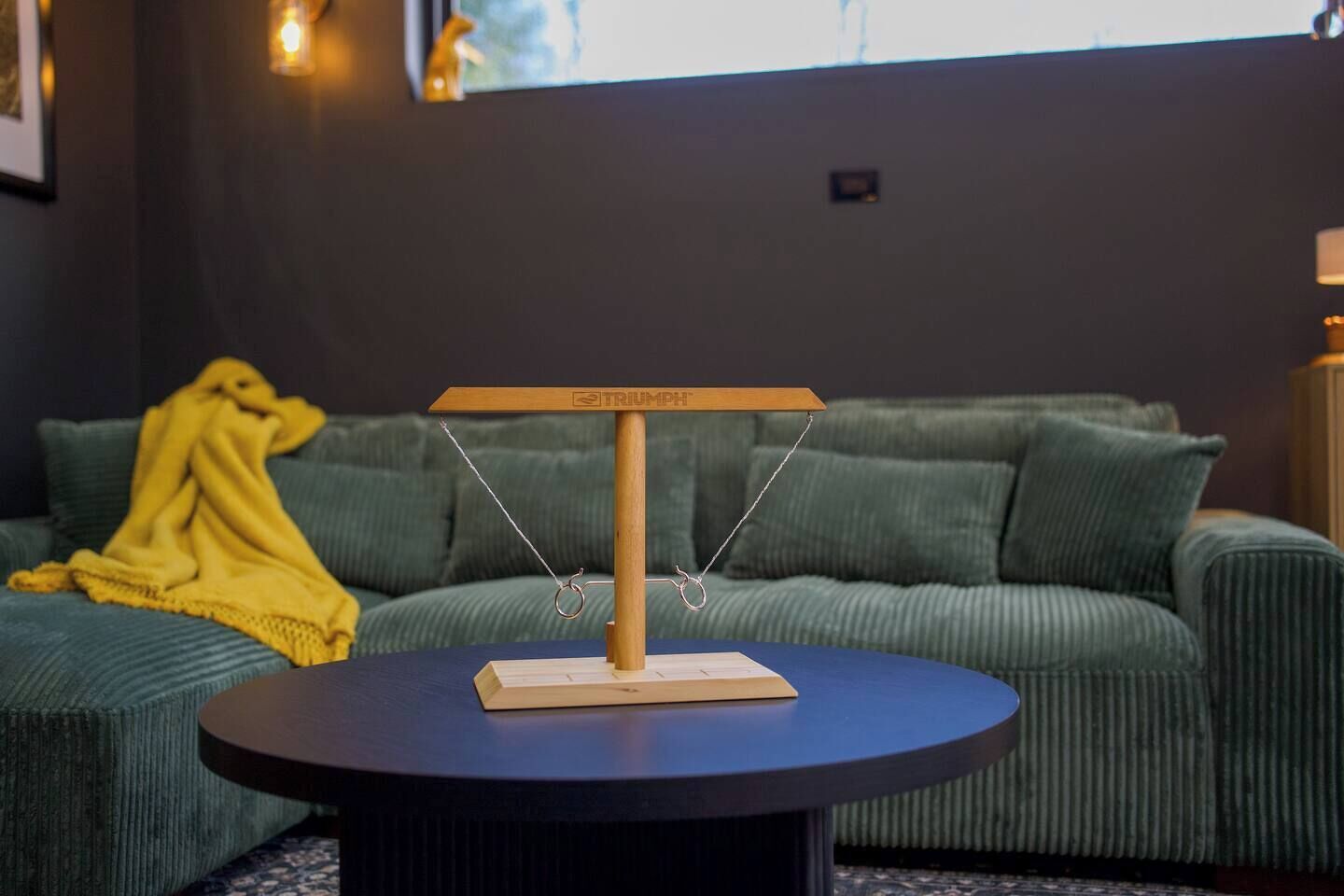 En skalamodel på et bord med en grøn sofa og et gult tæppe i baggrunden.
