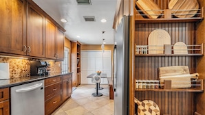 A modern kitchen with wooden cabinets, a stainless steel refrigerator, and a dining area with a table and chairs.
