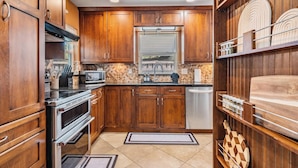 A kitchen with wooden cabinets, stainless steel appliances, and a window above the sink.