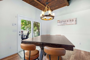 A dining area with a large wooden table, four leather chairs, and a chandelier.