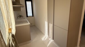 Ein modernes, minimalistisches Zimmer mit einer Küchenzeile, einem großen Kleiderschrank und einem Fenster mit Tageslicht.