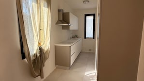 Eine Küche mit weißer Arbeitsplatte, einem eingebauten Ofen und einem Fenster mit Vorhängen.